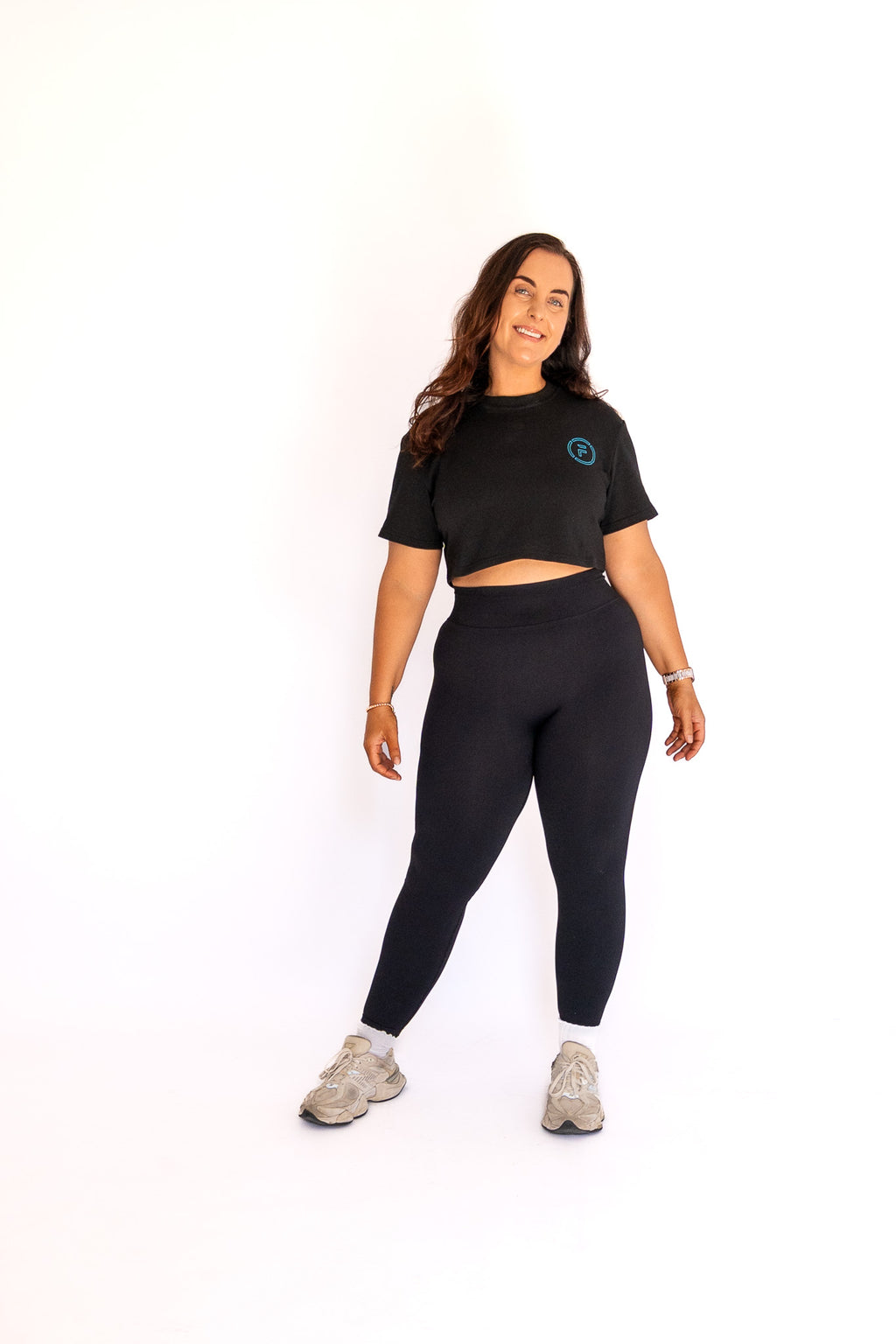 Woman wearing a black crop top and leggings on a white background