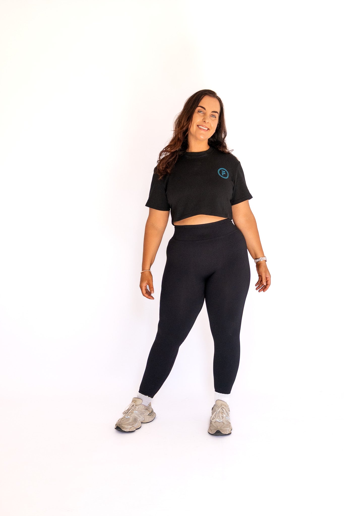 Woman wearing a black crop top and leggings on a white background