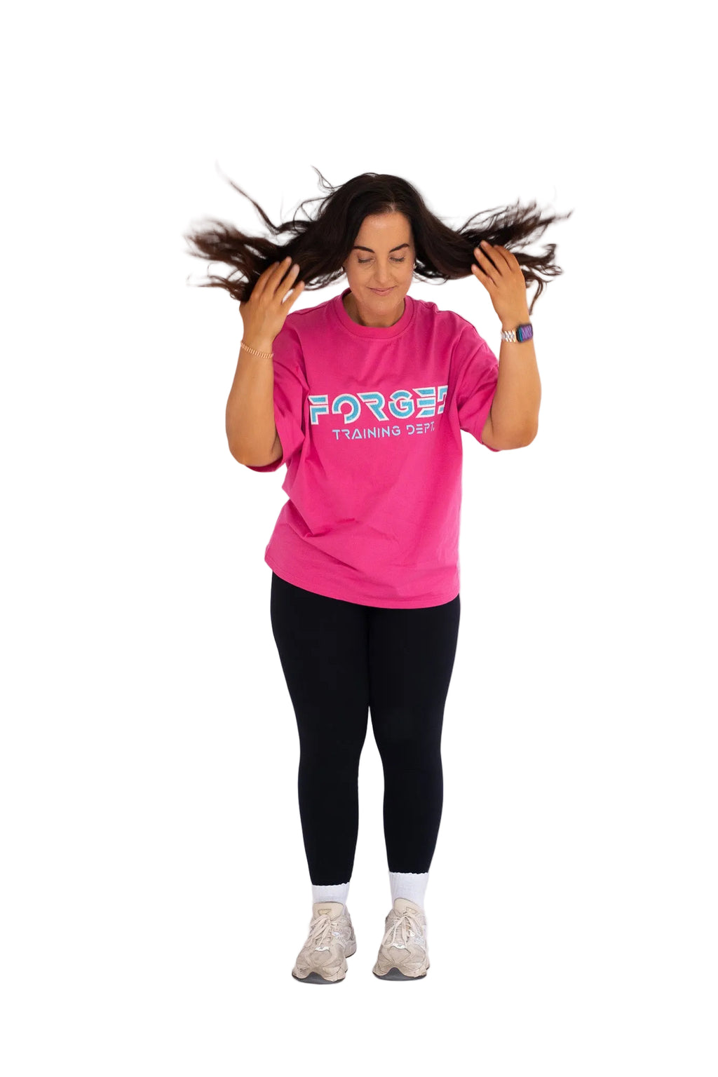 Person wearing a pink t-shirt with text, black leggings, and white sneakers on a light gray background