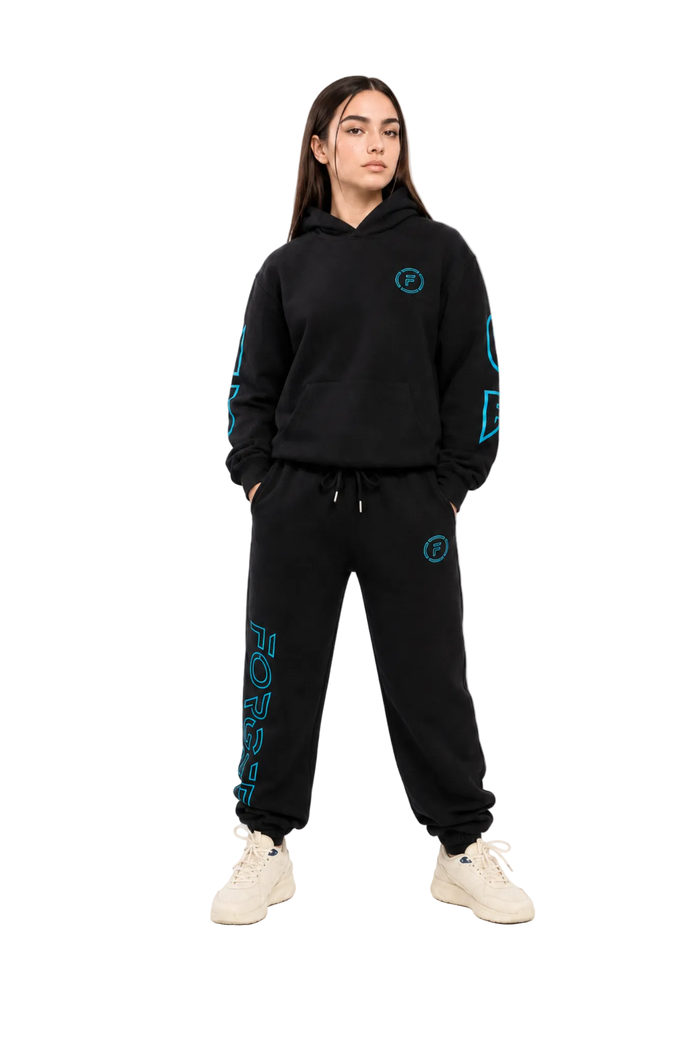 A woman modeling a black hoodie and matching sweatpants set with bright teal graphic prints, paired with off-white sneakers, against a plain white studio background.