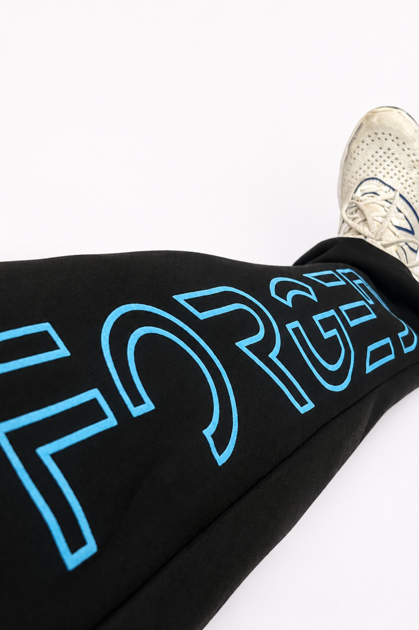 Black sweatpants with a large light blue outlined 'FORGED' graphic on the leg, shown with a white athletic shoe on a plain white background.
