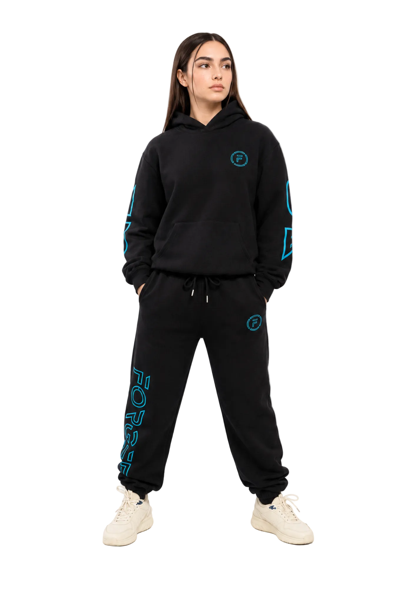 A woman modeling a black two-piece tracksuit with bright teal-blue graphic accents. The set includes a pullover hoodie with geometric sleeve prints and a matching sweatpants jogger with vertical text on the leg and a circular chest logo.