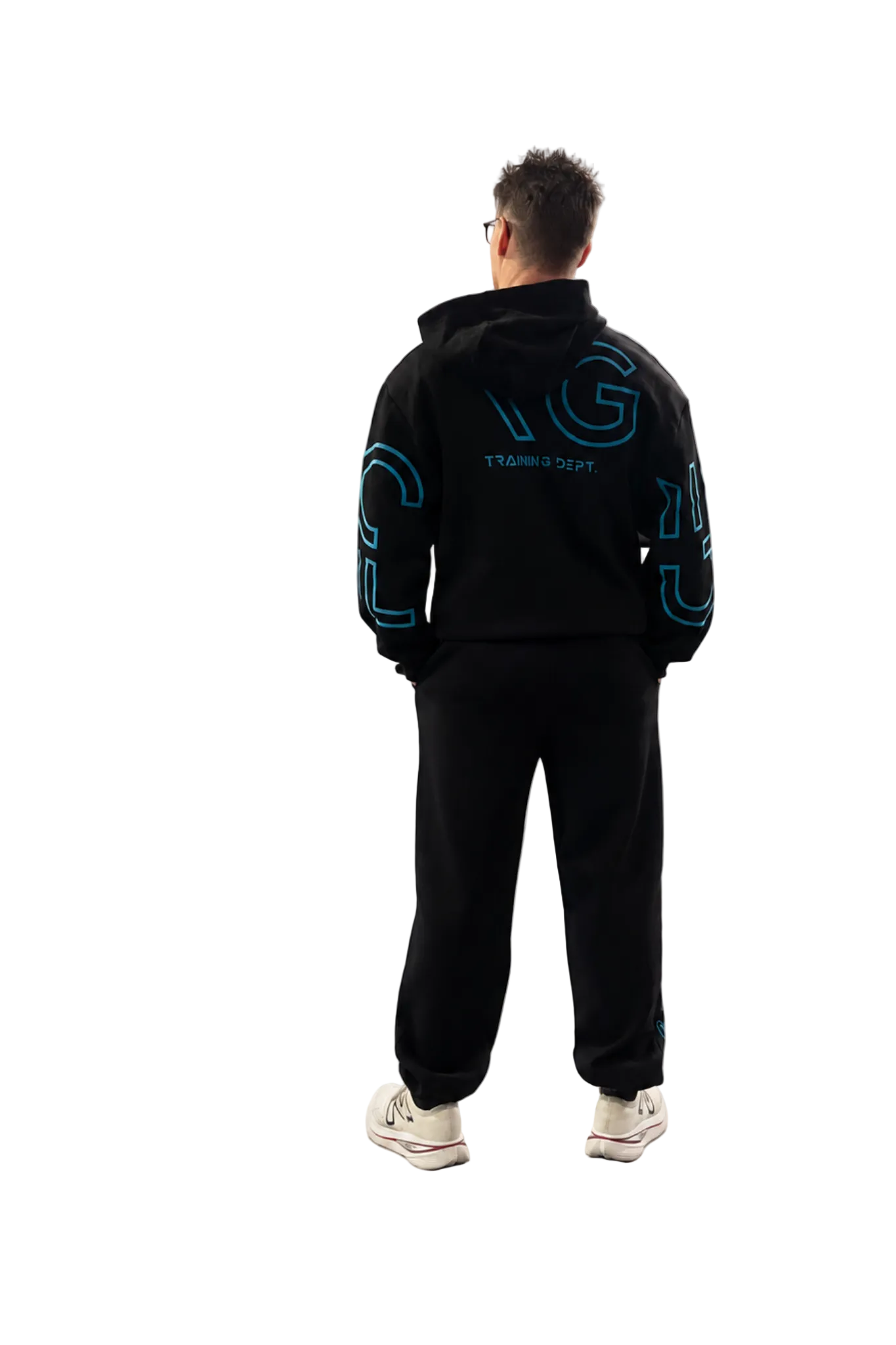 A man viewed from behind wearing a black hoodie and sweatpants set, featuring bright blue outlined graphic lettering on the back and sleeves, with white sneakers, against a plain white studio background.