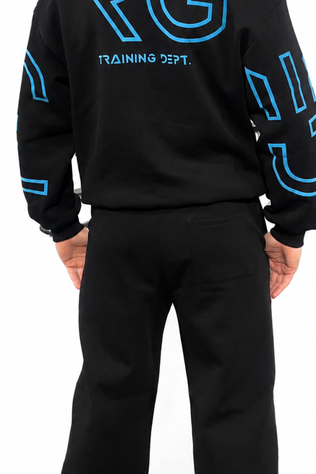 A person shown from the back wearing a black sweatshirt with bright blue outlined graphics and the words 'TRAINING DEPT.' across the upper back, paired with black pants, on a plain white background.
