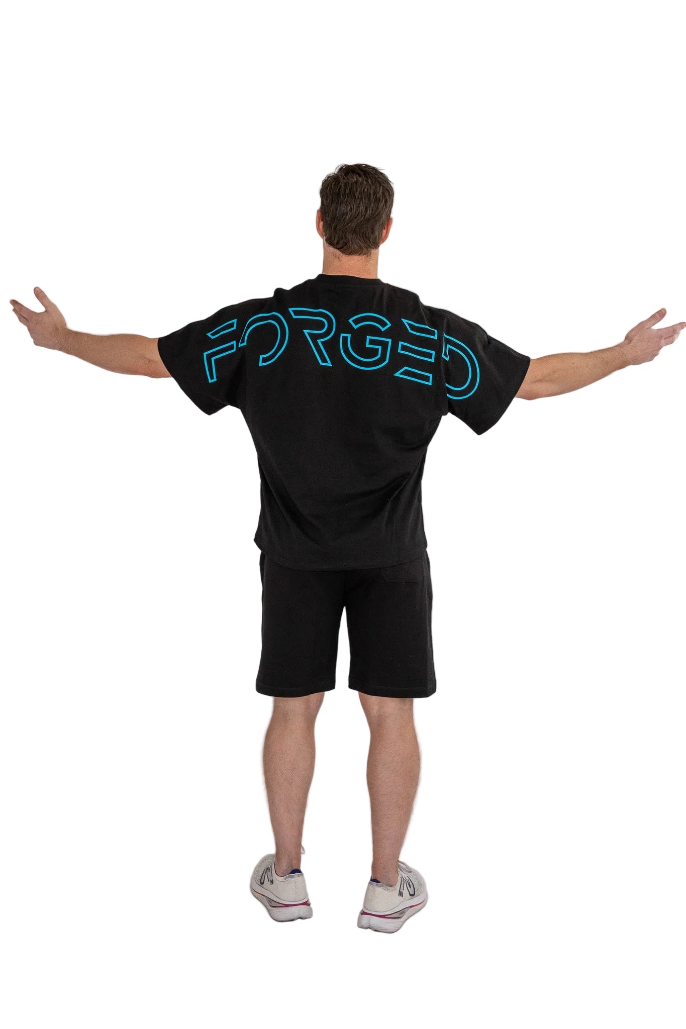 Person wearing a black t-shirt with 'FORGED' printed on the back against a white background
