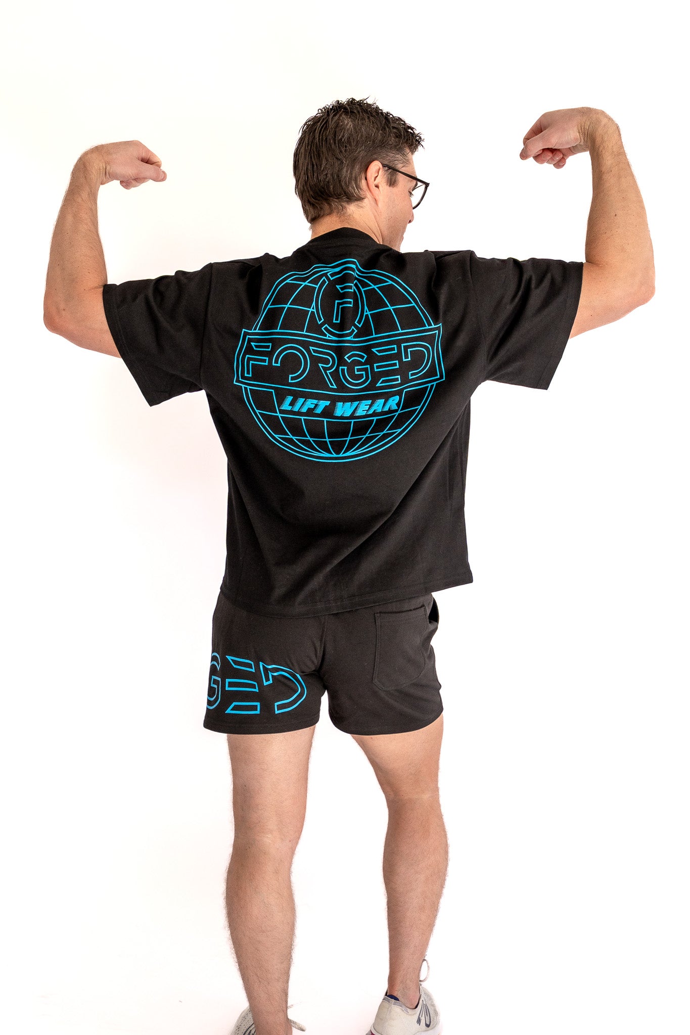 Person wearing a black t-shirt and shorts with 'Forged' branding on a white background