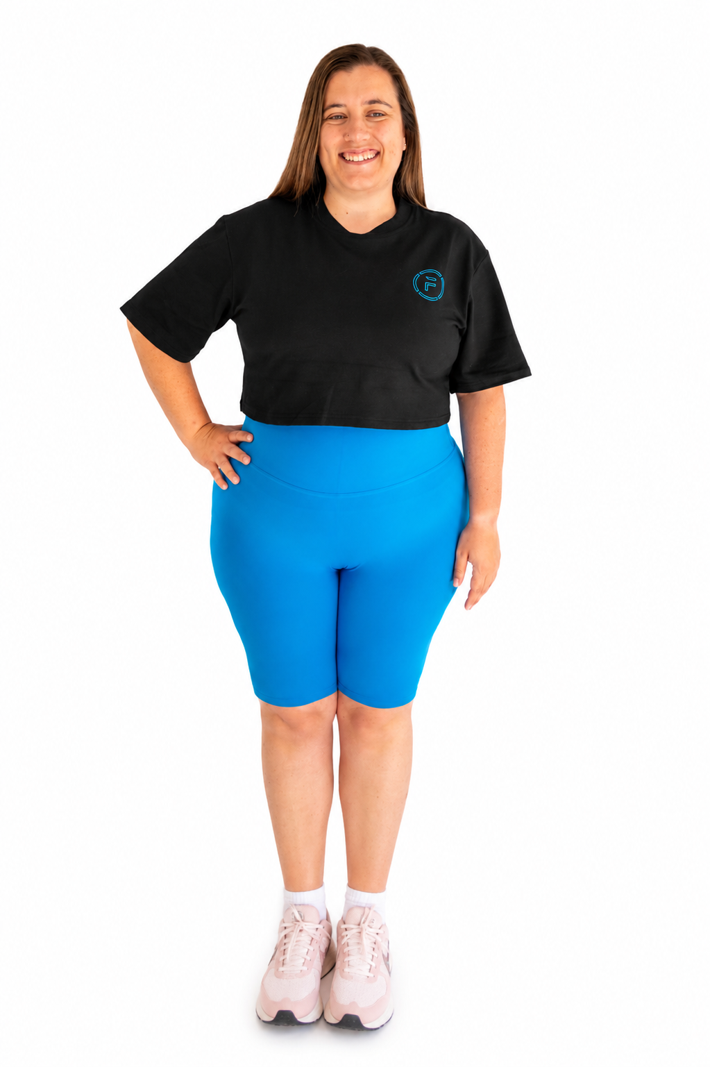 A woman modeling a black short-sleeve crop top and bright blue fitted bike shorts against a plain white background.