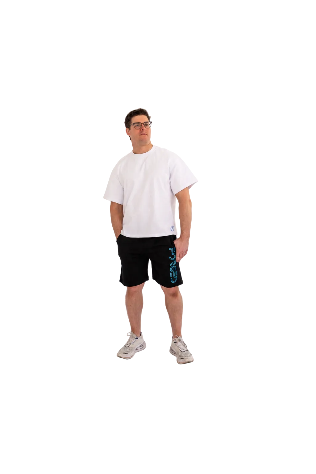 A man wearing a white t-shirt, black athletic shorts with a blue vertical logo, and light gray sneakers, standing against a seamless white studio background.