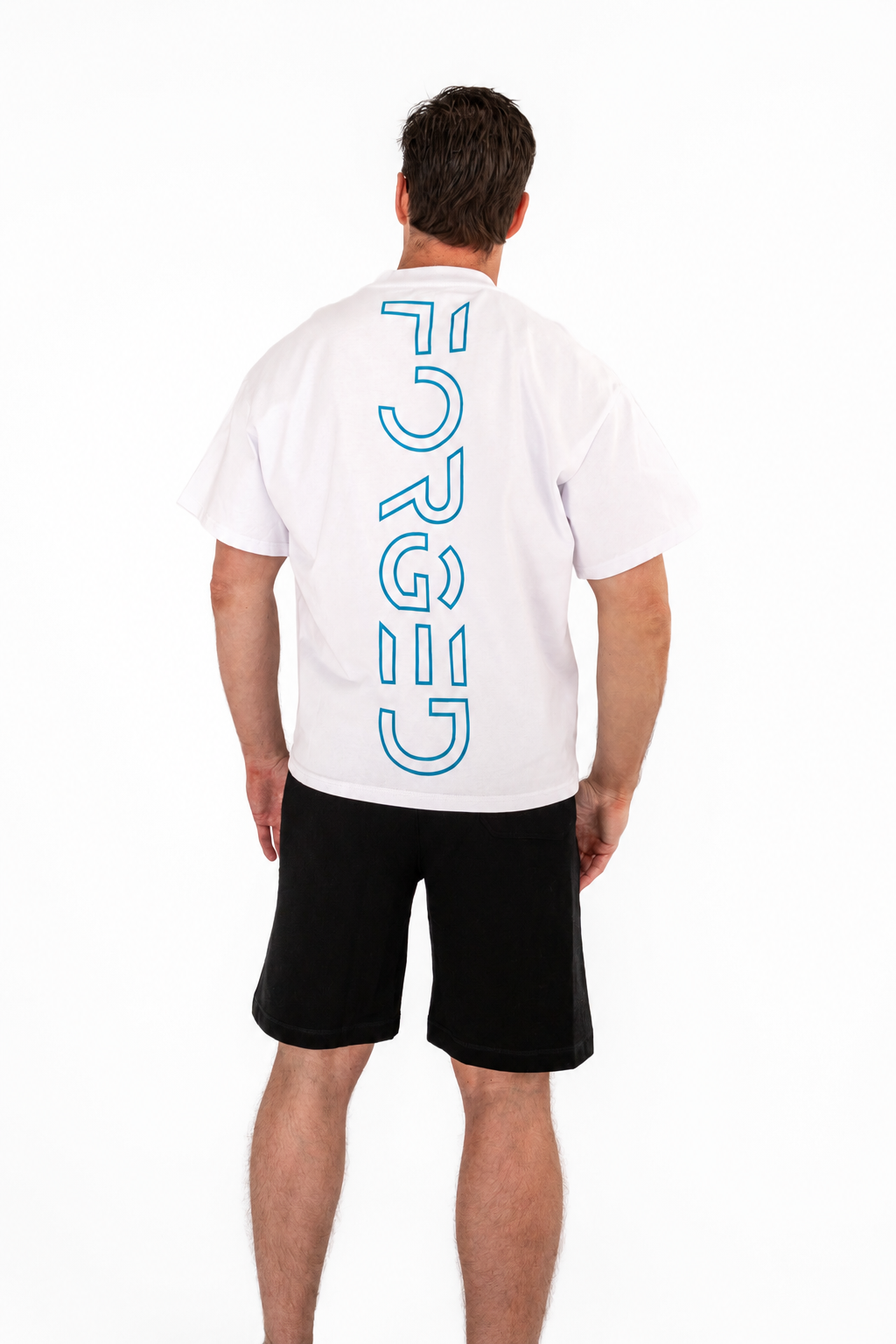 A man viewed from the back wearing a white t-shirt with a vertical blue 'FORGED' logo and black shorts, against a plain white background.