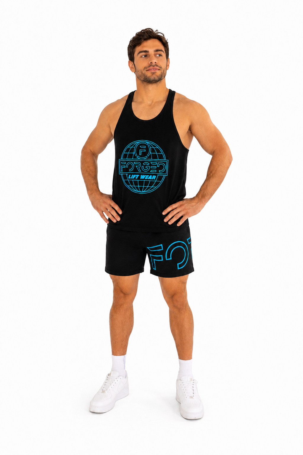 A man modeling a black athletic tank top and matching shorts set with bright blue graphic prints, paired with white socks and white sneakers, against a plain white background.